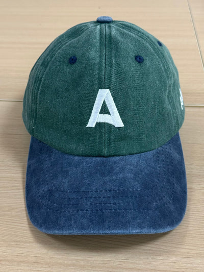 White geometric A embroidery on a green and navy Classic Cap