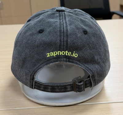 Lime zapnote.io lettering above the back opening of a charcoal Classic Cap