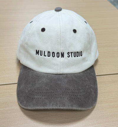 Muldoon Studio lettering on a cream and charcoal Classic Cap