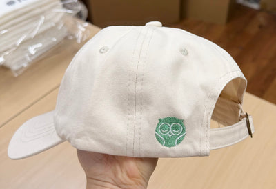 Green owl embroidery on the side of an off-white Classic Cap